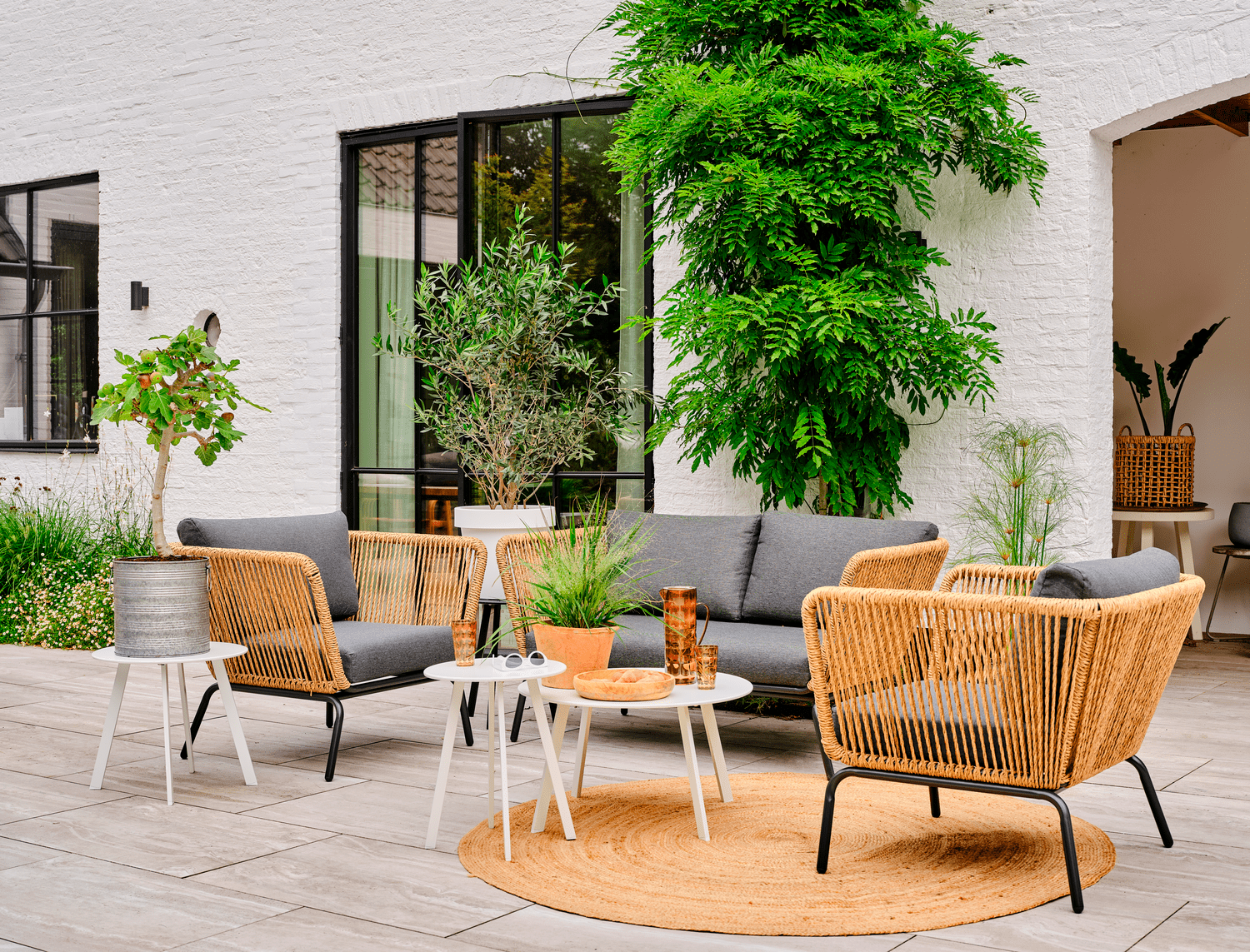 Mooie natuurlijke en toch moderne tuinset voor een wit huis met zwarte kozijnen